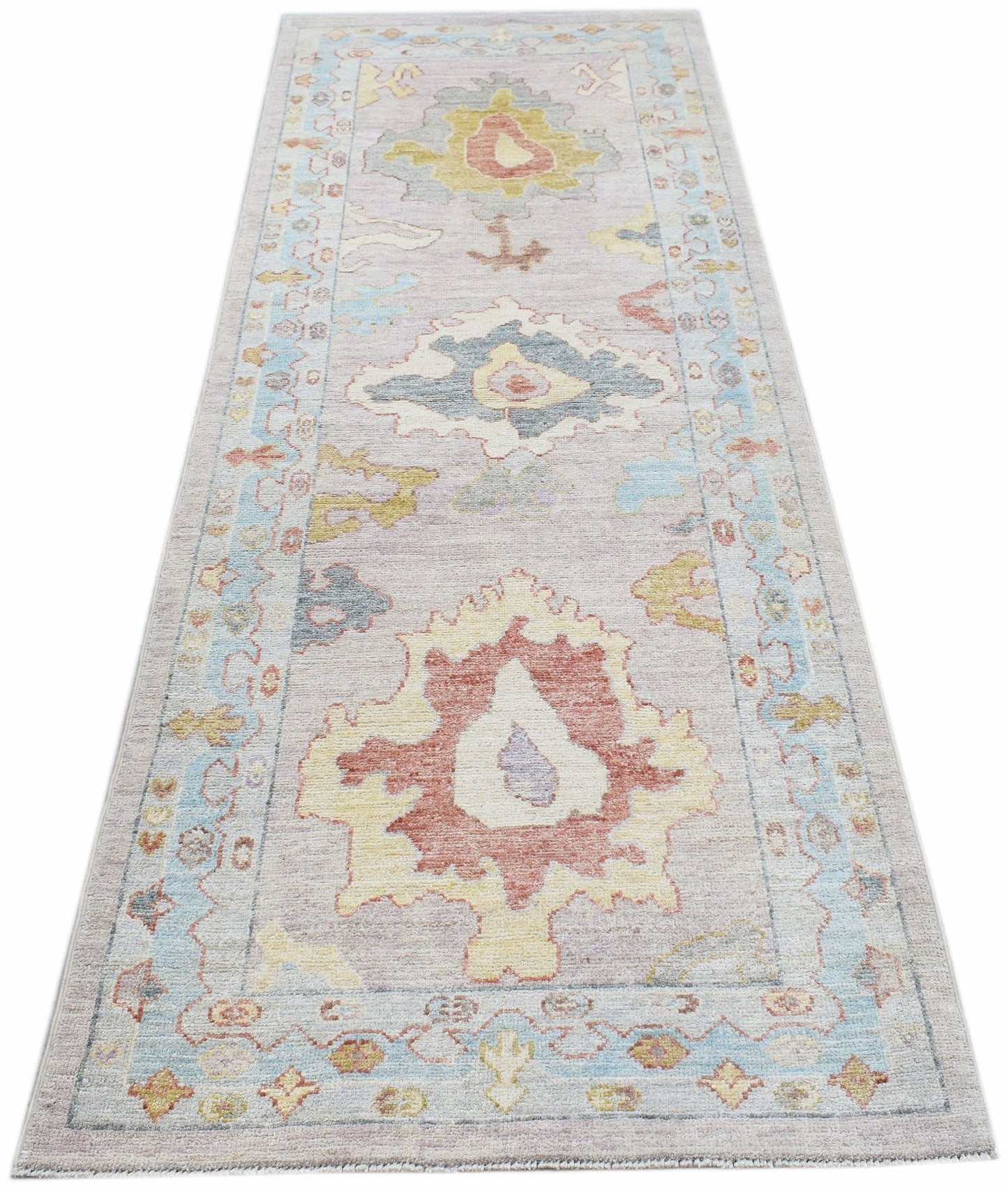 A handwoven transitional Oushak runner rug featuring a floral pattern in soft, muted colors.
