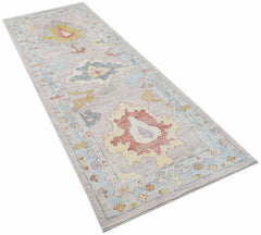 A handwoven wool runner rug featuring a transitional Oushak pattern in soft, muted tones.