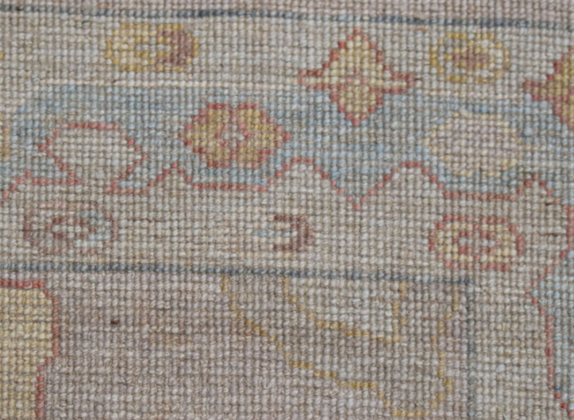 A close-up view of a handwoven transitional Oushak runner featuring a floral pattern in wool.