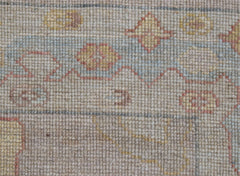 A close-up view of a handwoven transitional Oushak runner featuring a floral pattern in wool.