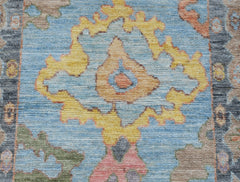 A handwoven transitional Oushak runner featuring a floral pattern in blue, yellow, and soft tones.