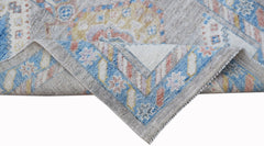 A handwoven wool runner rug featuring a transitional floral pattern in blue, grey, and soft tones.