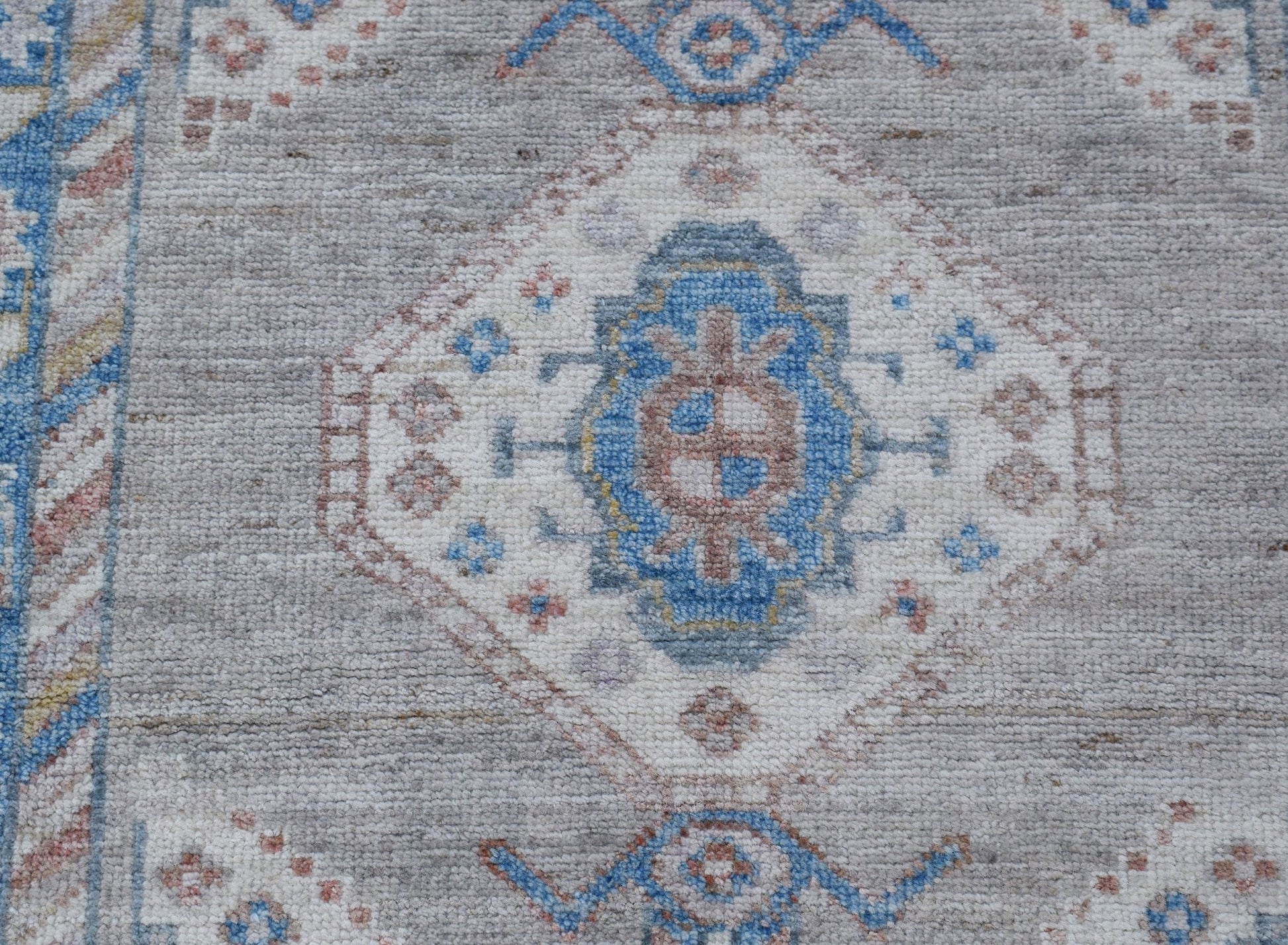 A handwoven wool runner featuring a transitional Oushak pattern in blue, grey, and soft pink tones.