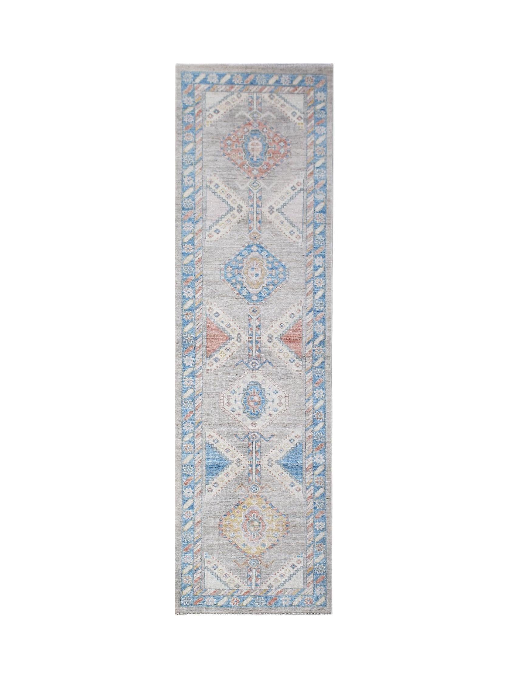 A handwoven wool runner rug featuring a transitional Oushak pattern in blue, grey, and peach tones.