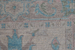 A close-up of a handwoven wool runner featuring a transitional floral pattern in blue and grey.