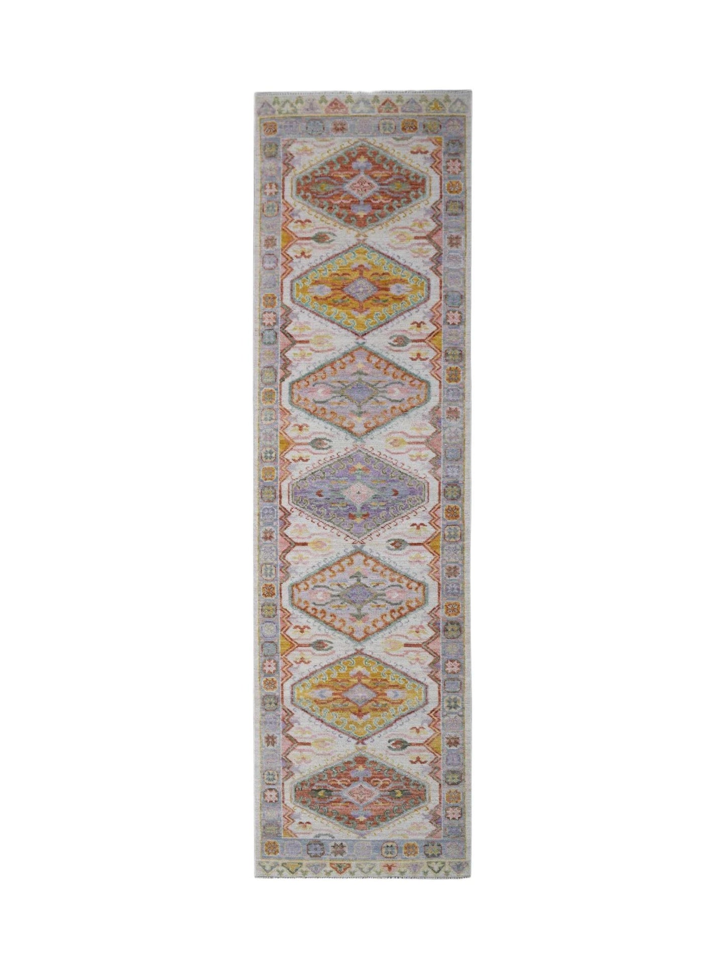 A handwoven wool runner rug featuring a repeating diamond pattern in soft, multicolored tones.