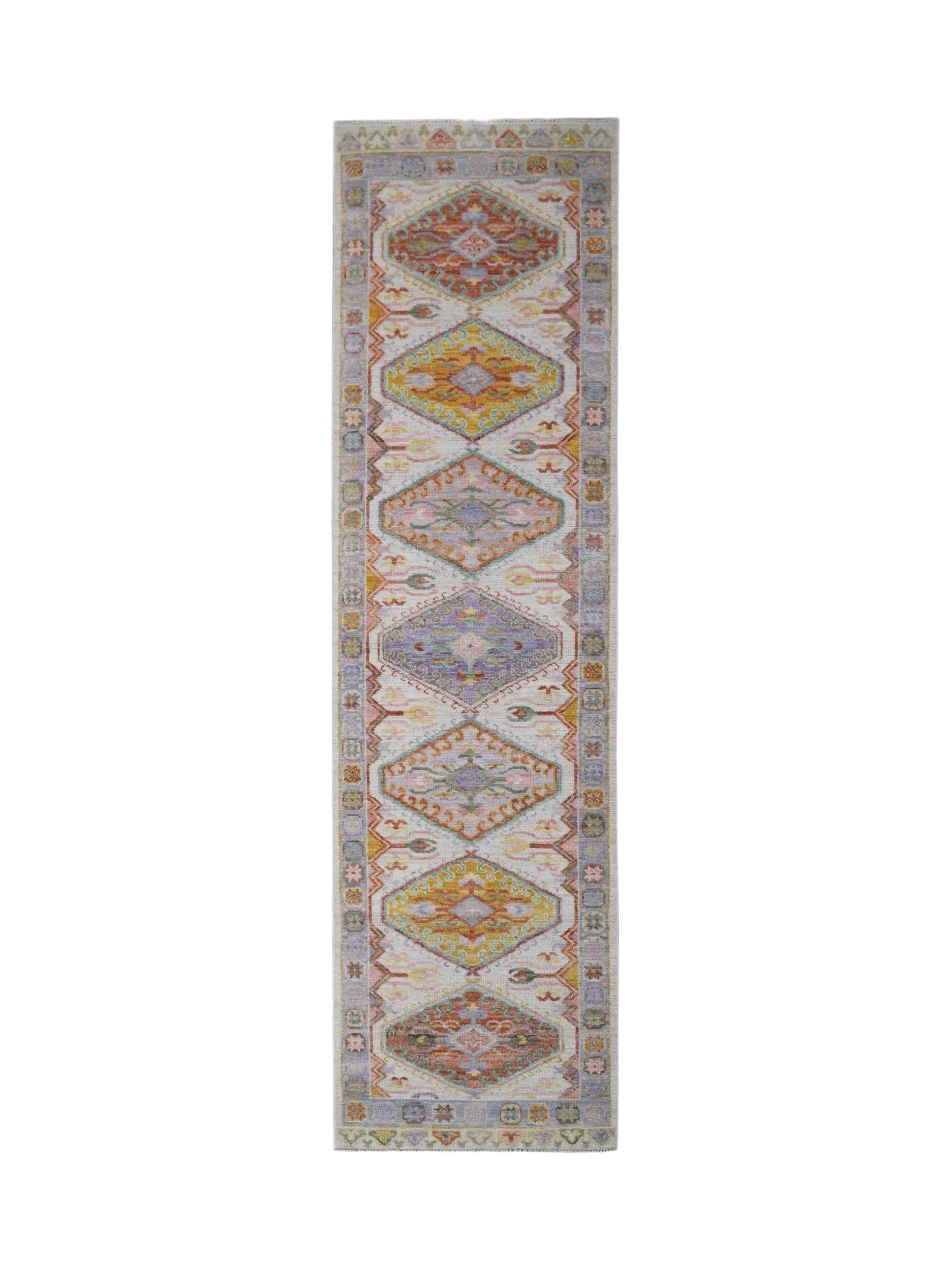 A handwoven wool runner rug featuring a repeating diamond pattern in soft, multicolored tones.