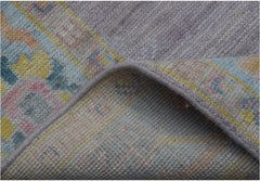 A folded handmade wool runner rug featuring a traditional pattern in soft pastel tones.