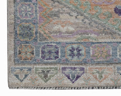 A close-up of a handwoven Oushak runner featuring a geometric border in blue, purple, and green.