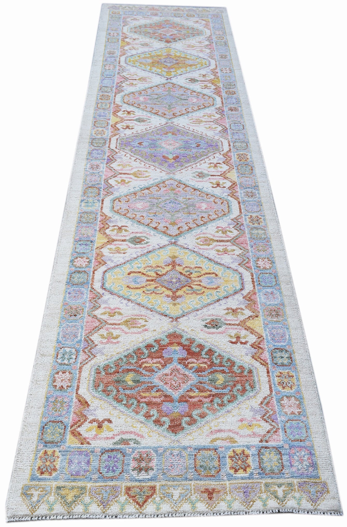 A handwoven wool runner rug featuring a series of colorful geometric medallions on a white field.