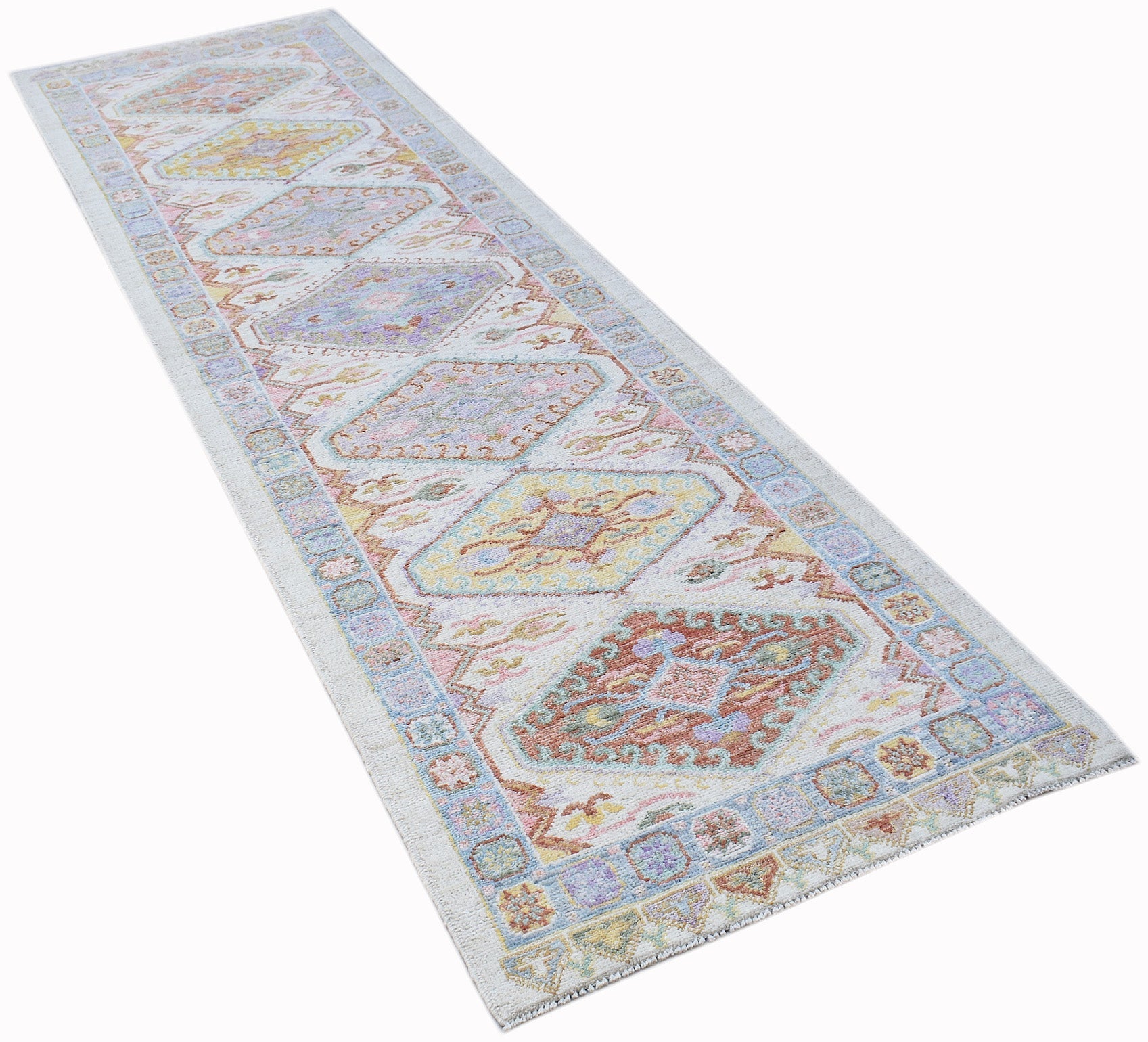 A handwoven wool runner rug featuring a transitional Oushak pattern in soft, multi-colored tones.