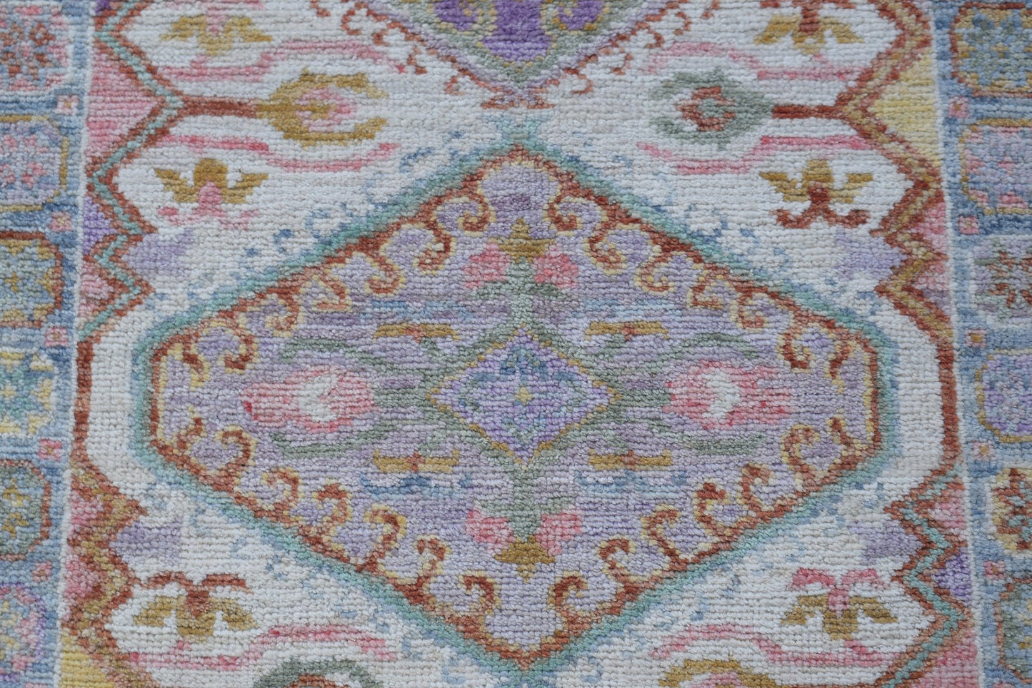 A handwoven wool runner rug featuring a transitional floral pattern in soft pastel colors.