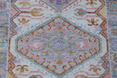 A handwoven wool runner rug featuring a transitional floral pattern in soft pastel colors.