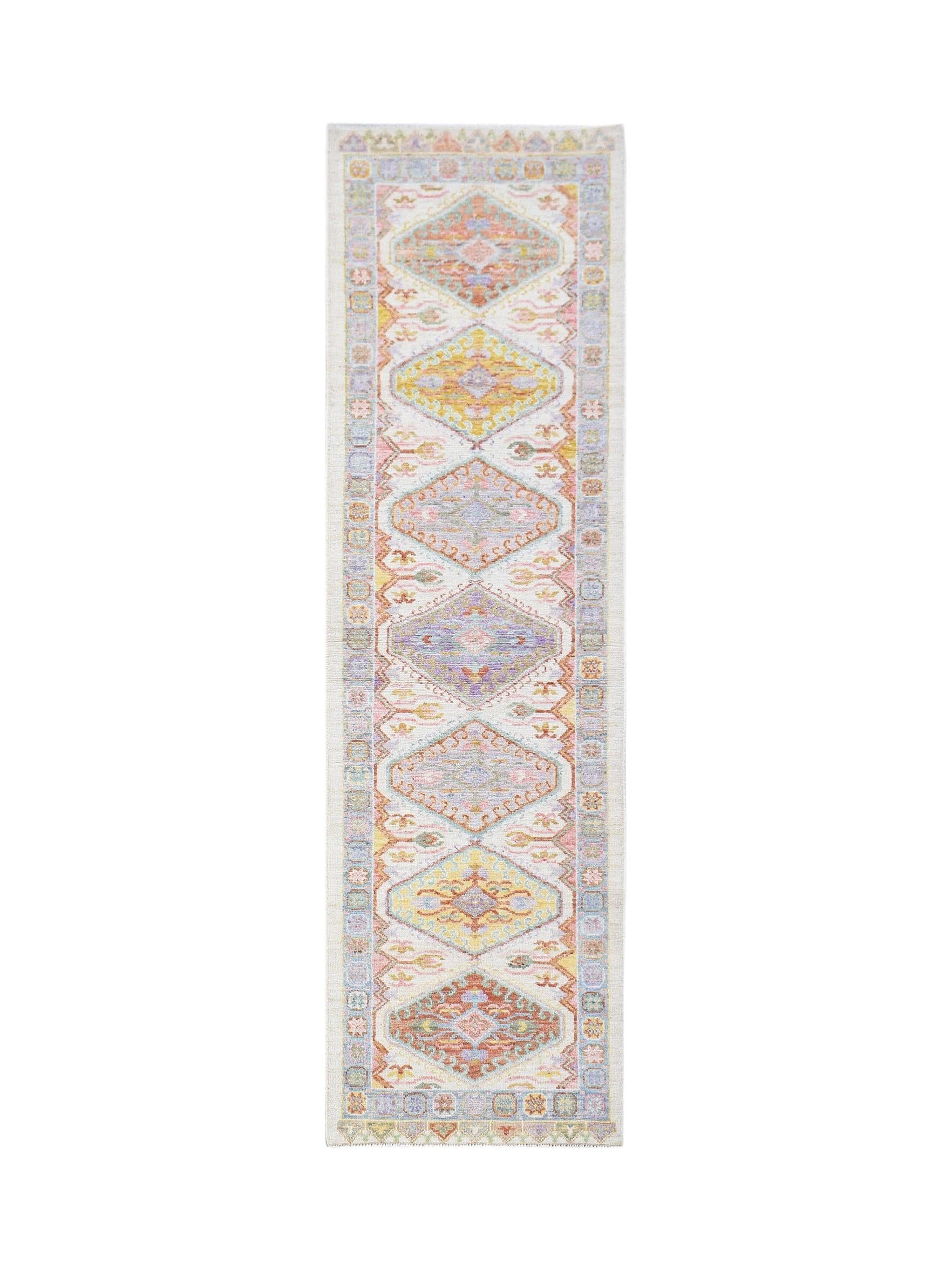 A handwoven wool runner rug featuring a transitional Oushak pattern in soft pastel colors.