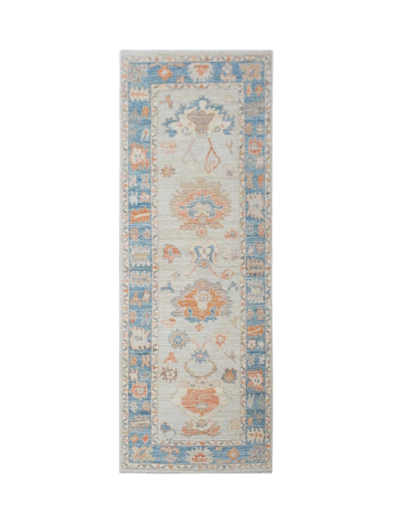 A handwoven wool runner rug featuring a transitional floral pattern in blue and orange tones.