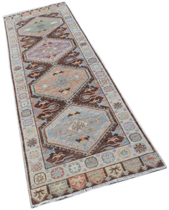 A handmade Afghan Oushak runner rug featuring a traditional geometric pattern in muted colors.