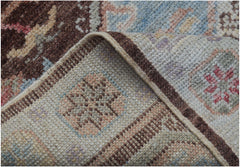 A close-up view of a handmade wool runner rug featuring a traditional pattern in brown and blue.