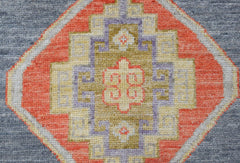 A handwoven Oushak runner featuring a geometric medallion in orange, purple, and gold on blue.