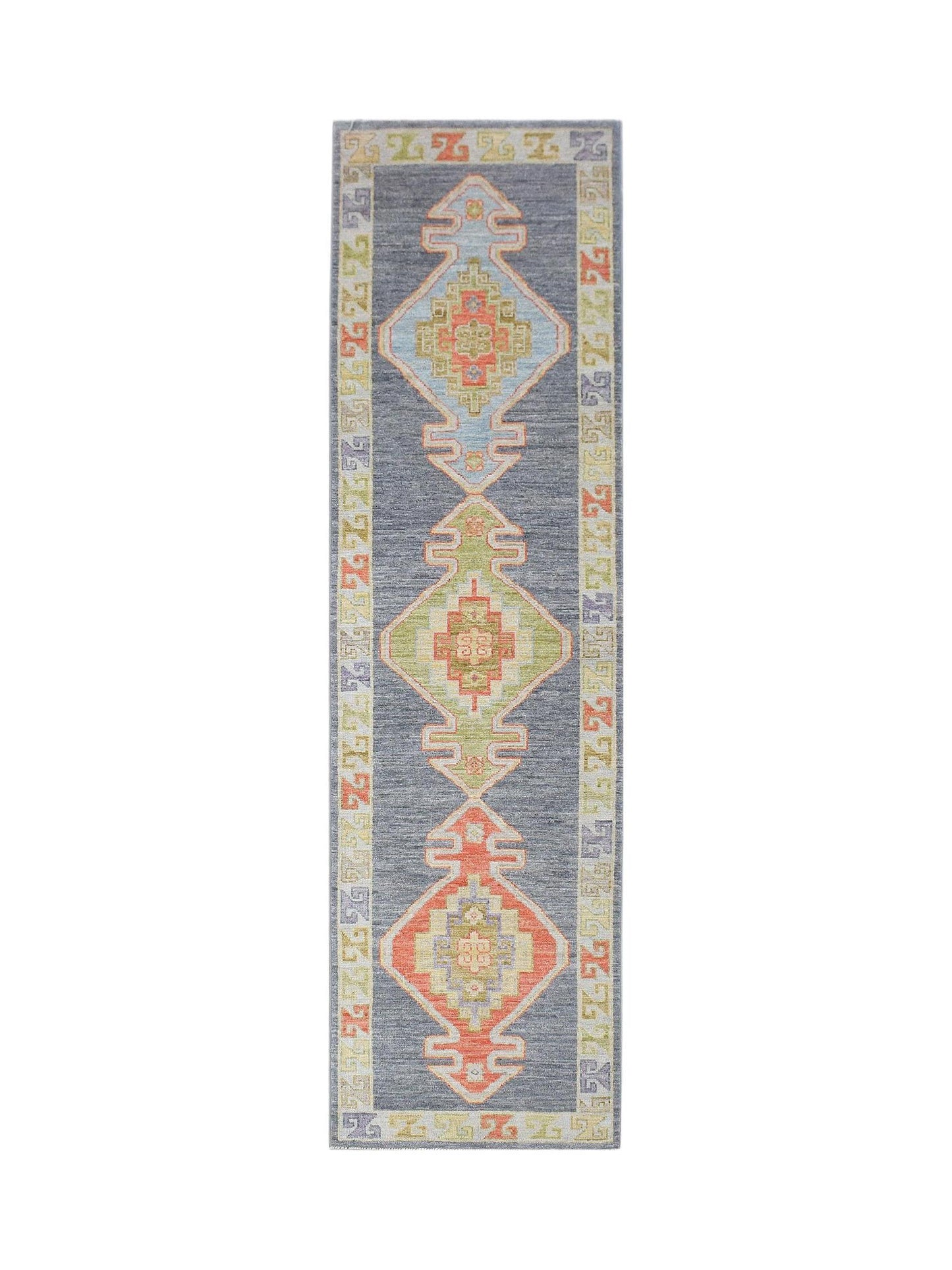 A handwoven wool runner rug featuring three geometric diamond medallions on a dark grey field.