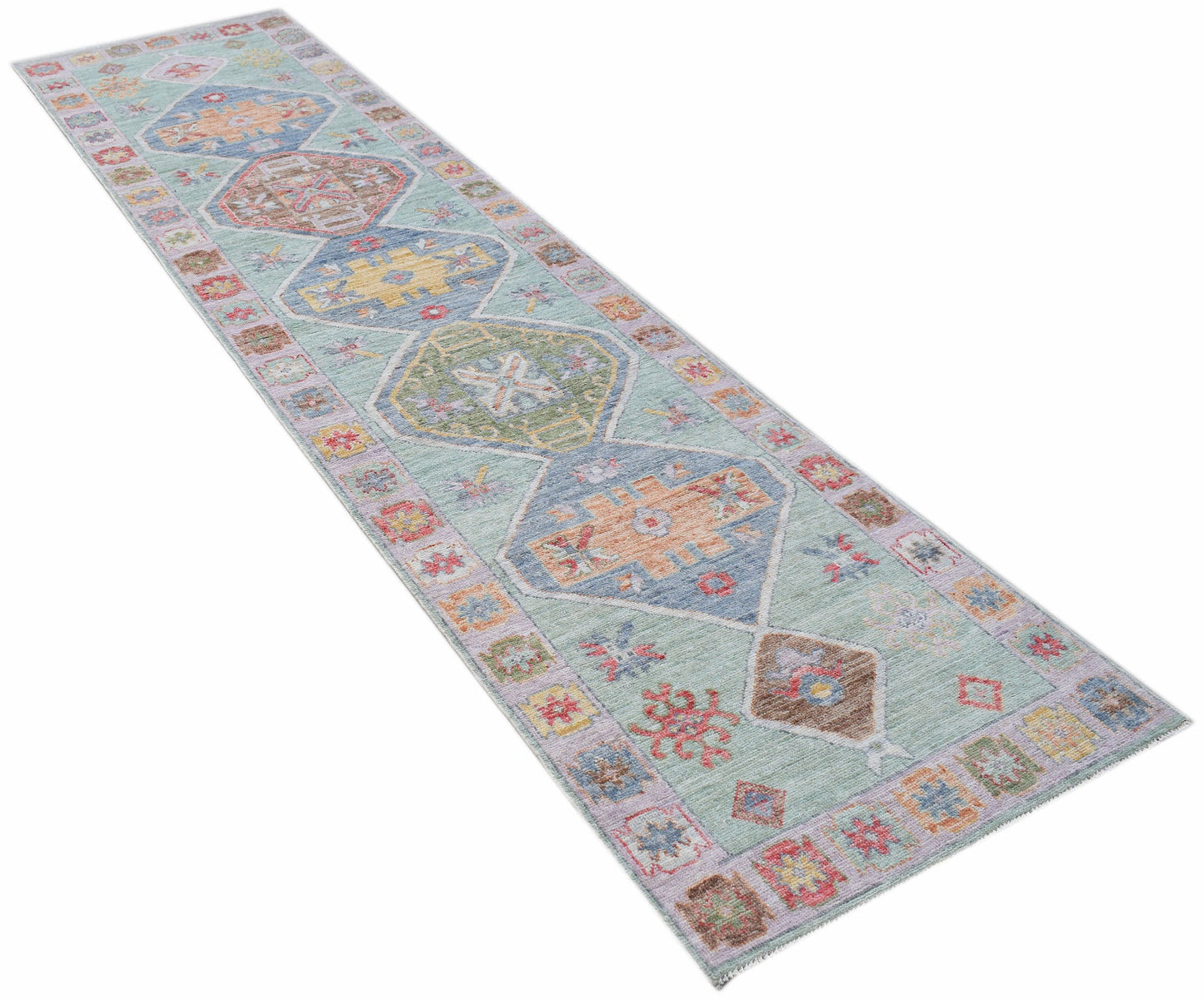 A handwoven wool runner rug featuring a light blue background with colorful geometric medallions.