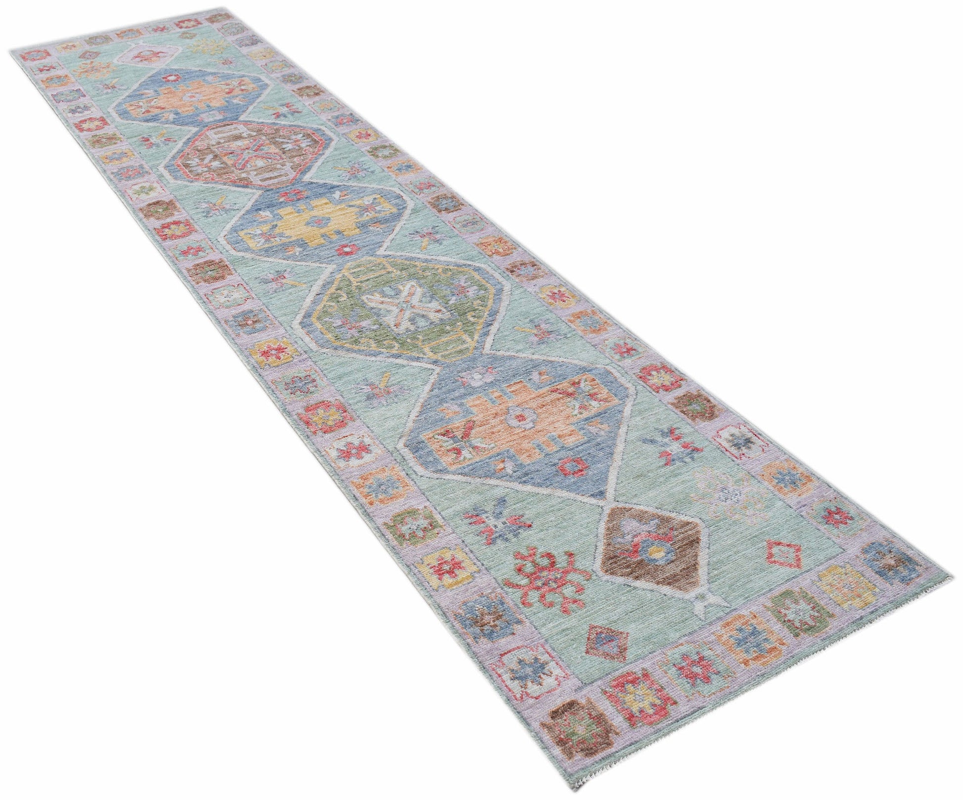 A handwoven wool runner rug featuring a light blue background with colorful geometric medallions.