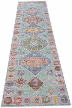 A handwoven transitional Oushak runner featuring geometric diamond motifs on a light green field.