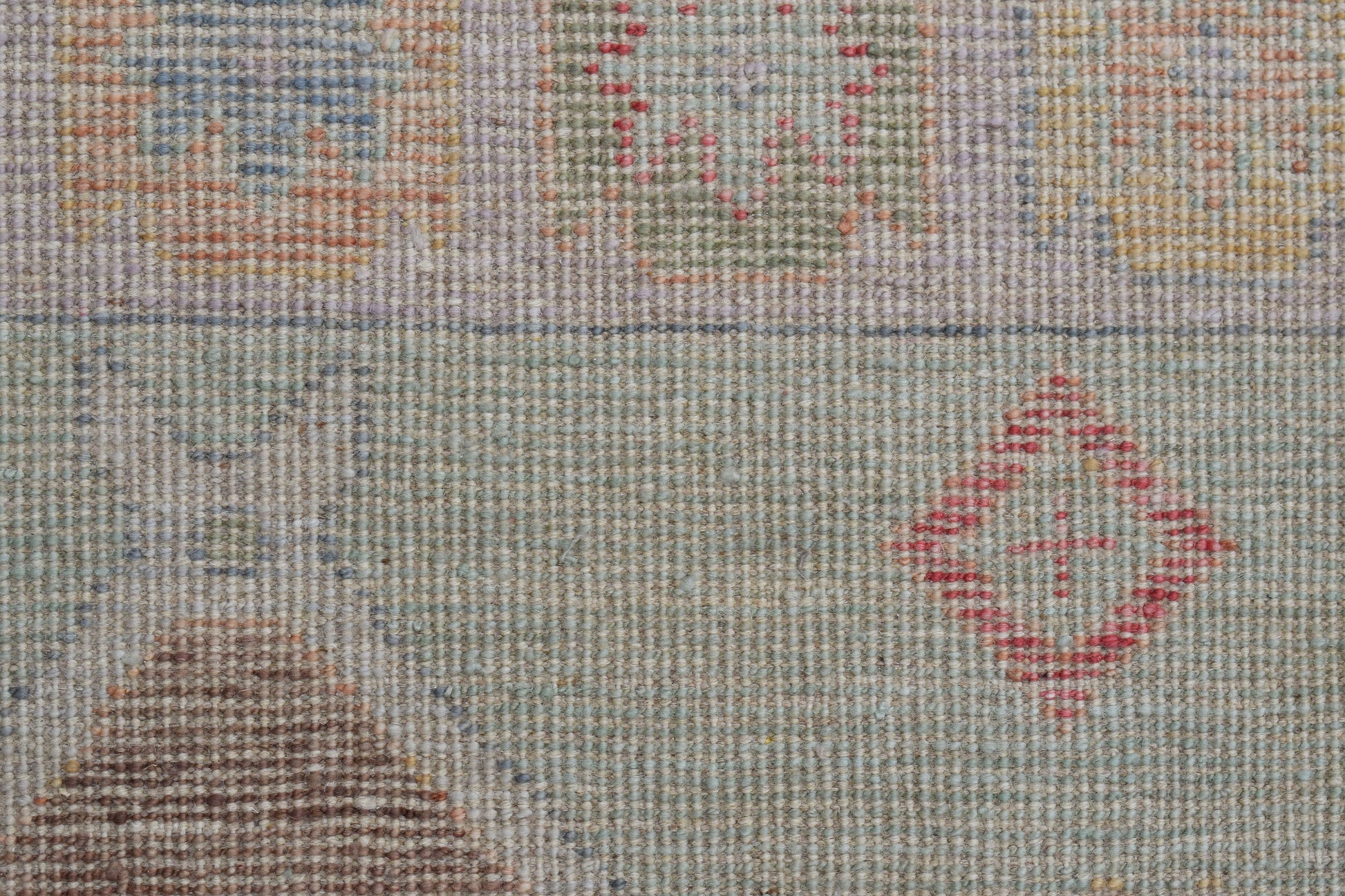 A handwoven wool runner featuring a transitional pattern with geometric motifs in muted tones.