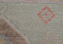 A handwoven wool runner featuring a light green field with a small red diamond motif.