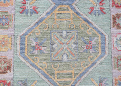 A handwoven transitional Oushak runner featuring a central geometric medallion in soft green tones.