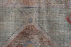 A close-up of a handwoven wool runner featuring a transitional Oushak pattern in muted tones.
