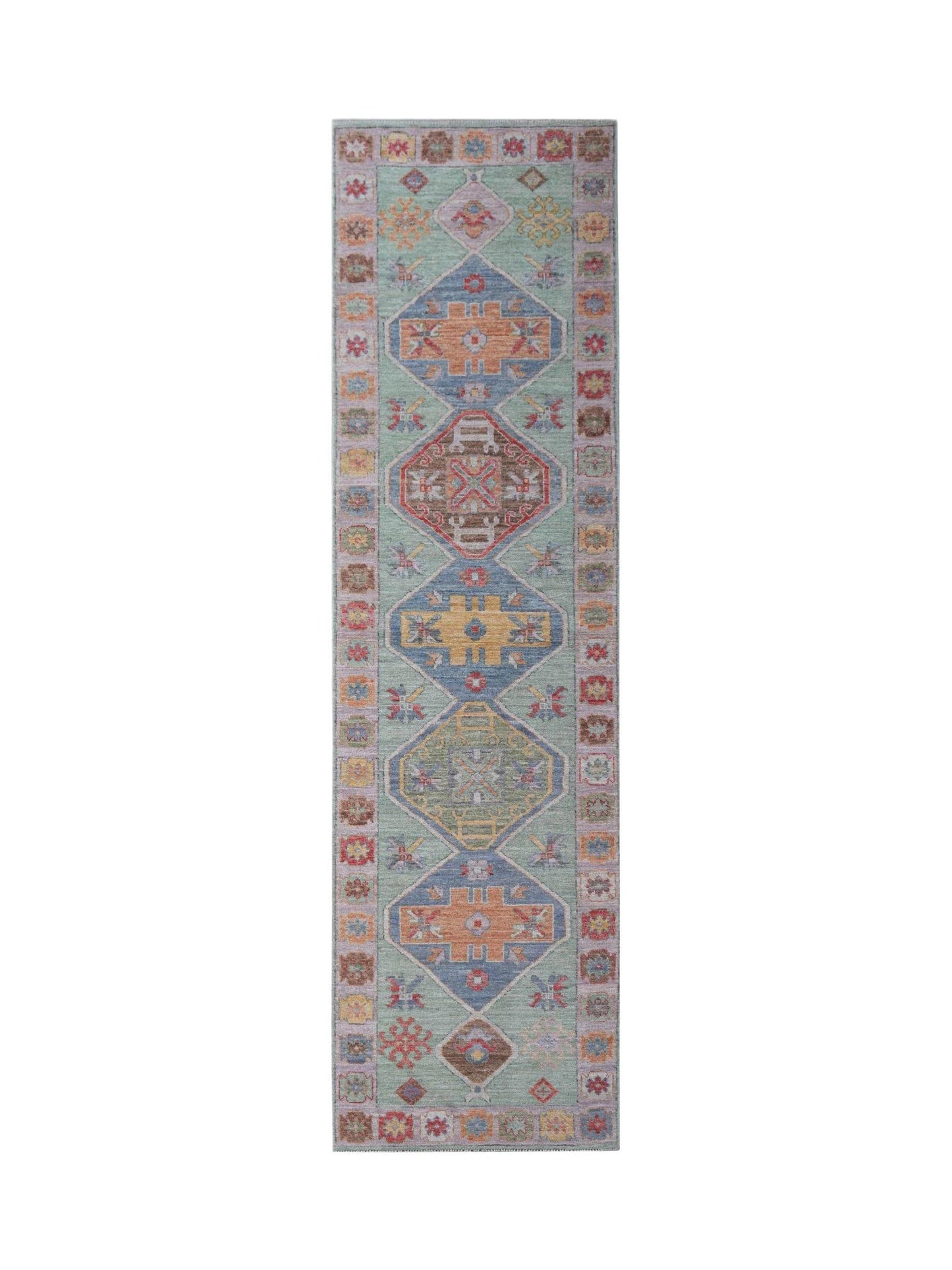A handwoven wool runner rug featuring a light green field with geometric medallions in muted tones.