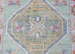 A transitional Oushak runner featuring a central geometric medallion in soft green and blue tones.