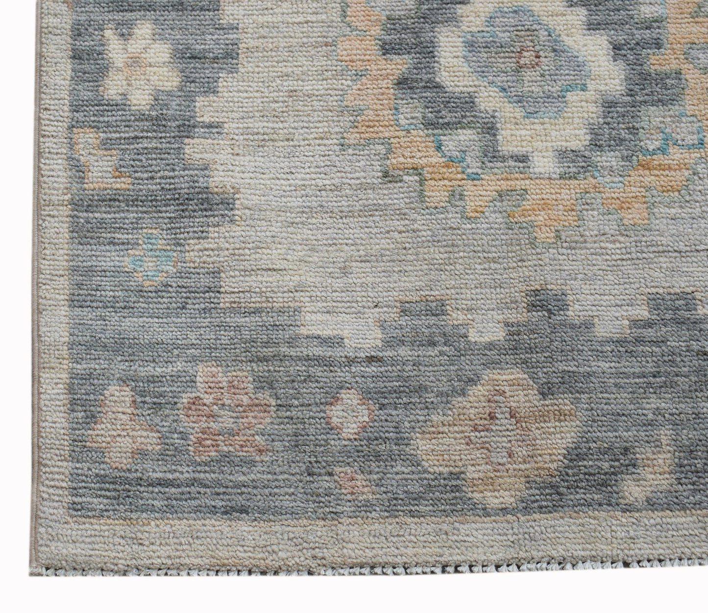 A handwoven wool runner rug featuring a transitional floral pattern in blue, beige, and pink tones.