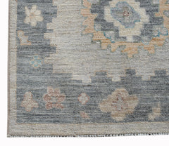 A handwoven wool runner rug featuring a transitional floral pattern in blue, beige, and pink tones.