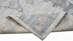 A handwoven transitional Oushak runner featuring a floral pattern in soft blue and neutral tones.