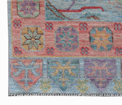 A handwoven wool runner featuring a colorful geometric pattern on a pink and blue background.