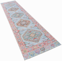 A handwoven transitional Oushak runner rug featuring a light blue field with geometric floral motifs.
