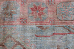 A close-up of a handwoven wool runner rug featuring a transitional floral pattern in soft tones.