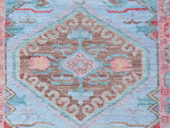 A handwoven transitional Oushak runner featuring a central floral medallion on a light blue field.