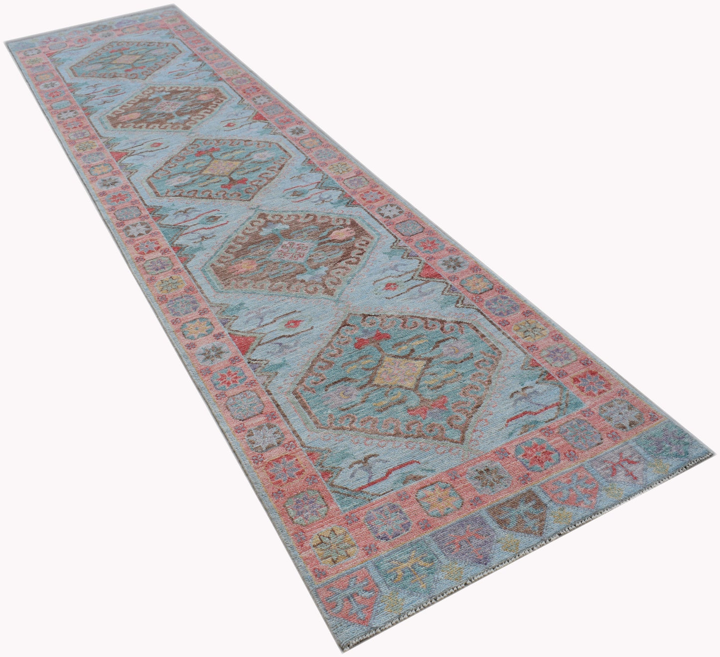 A handwoven wool runner rug featuring a light blue field with traditional geometric Oushak motifs.