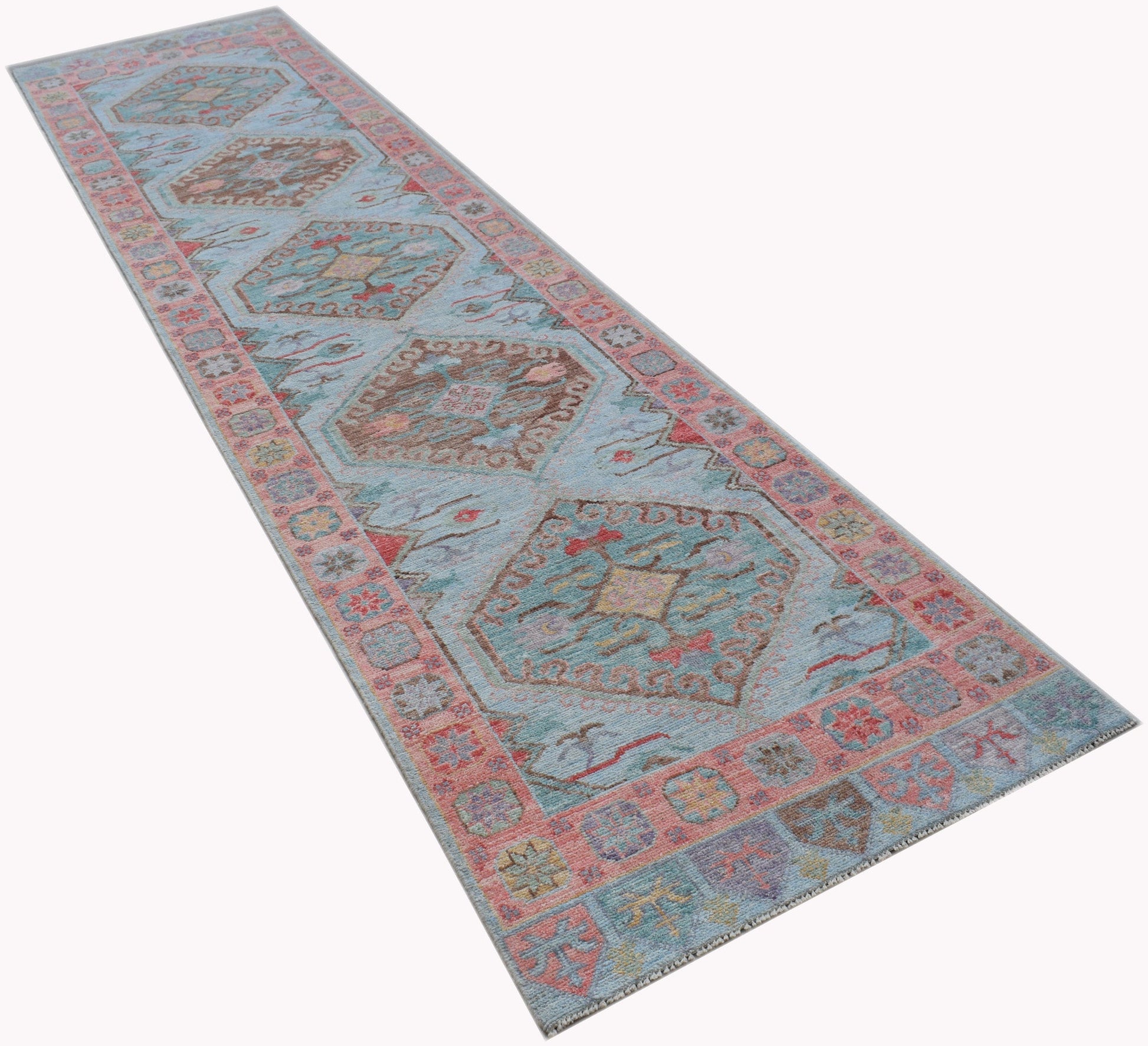 A handwoven wool runner rug featuring a light blue field with traditional geometric Oushak motifs.