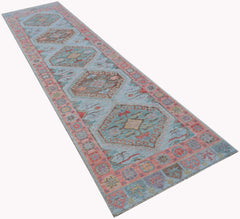 A handwoven wool runner rug featuring a light blue field with traditional geometric Oushak motifs.
