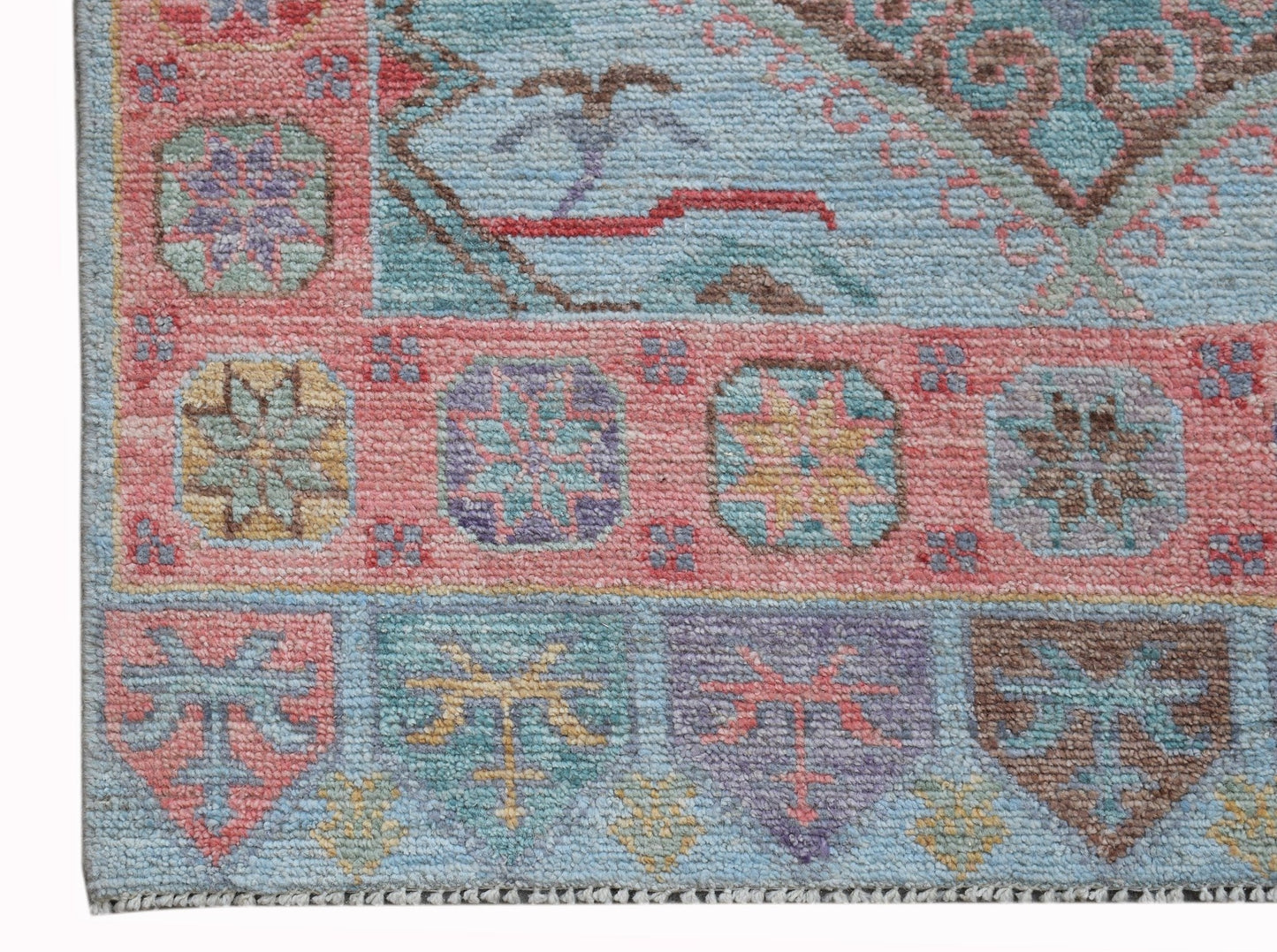 A handwoven transitional Oushak runner featuring a geometric floral pattern in soft pastel tones.