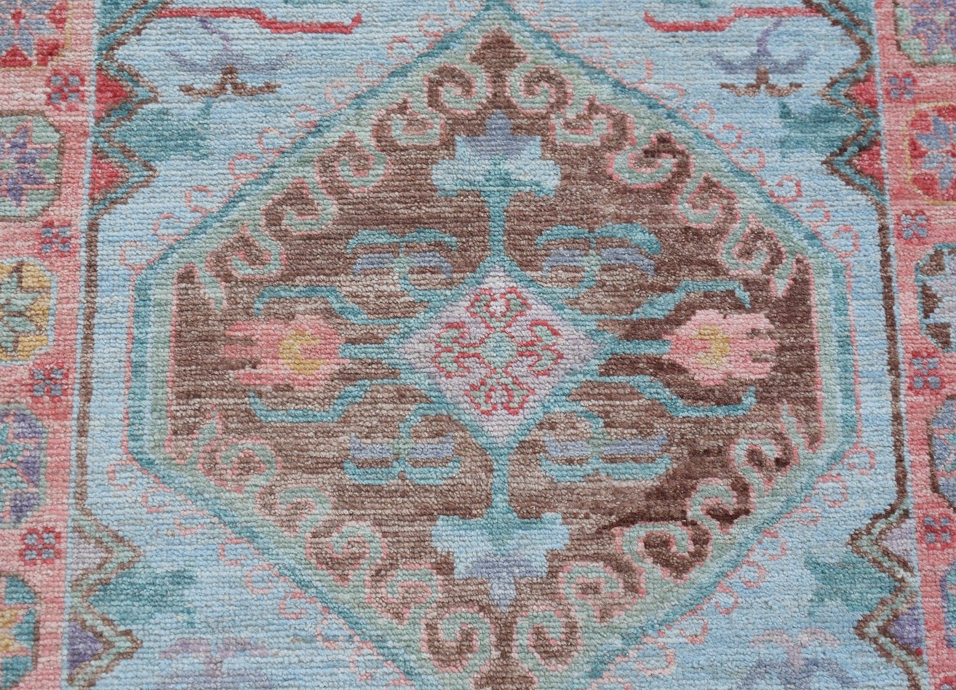 A transitional Oushak runner featuring a central brown medallion with floral motifs on a blue field.