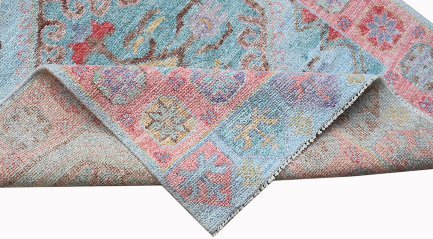 A handwoven wool runner with a floral pattern in shades of blue, pink, and yellow.