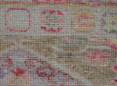 A close-up of a handwoven Oushak runner featuring a textured pattern in pink, yellow, and grey.