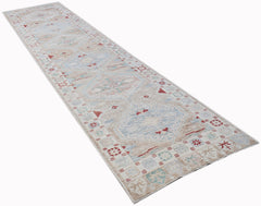 A long, handwoven wool runner rug featuring a transitional Oushak pattern in soft, muted tones.