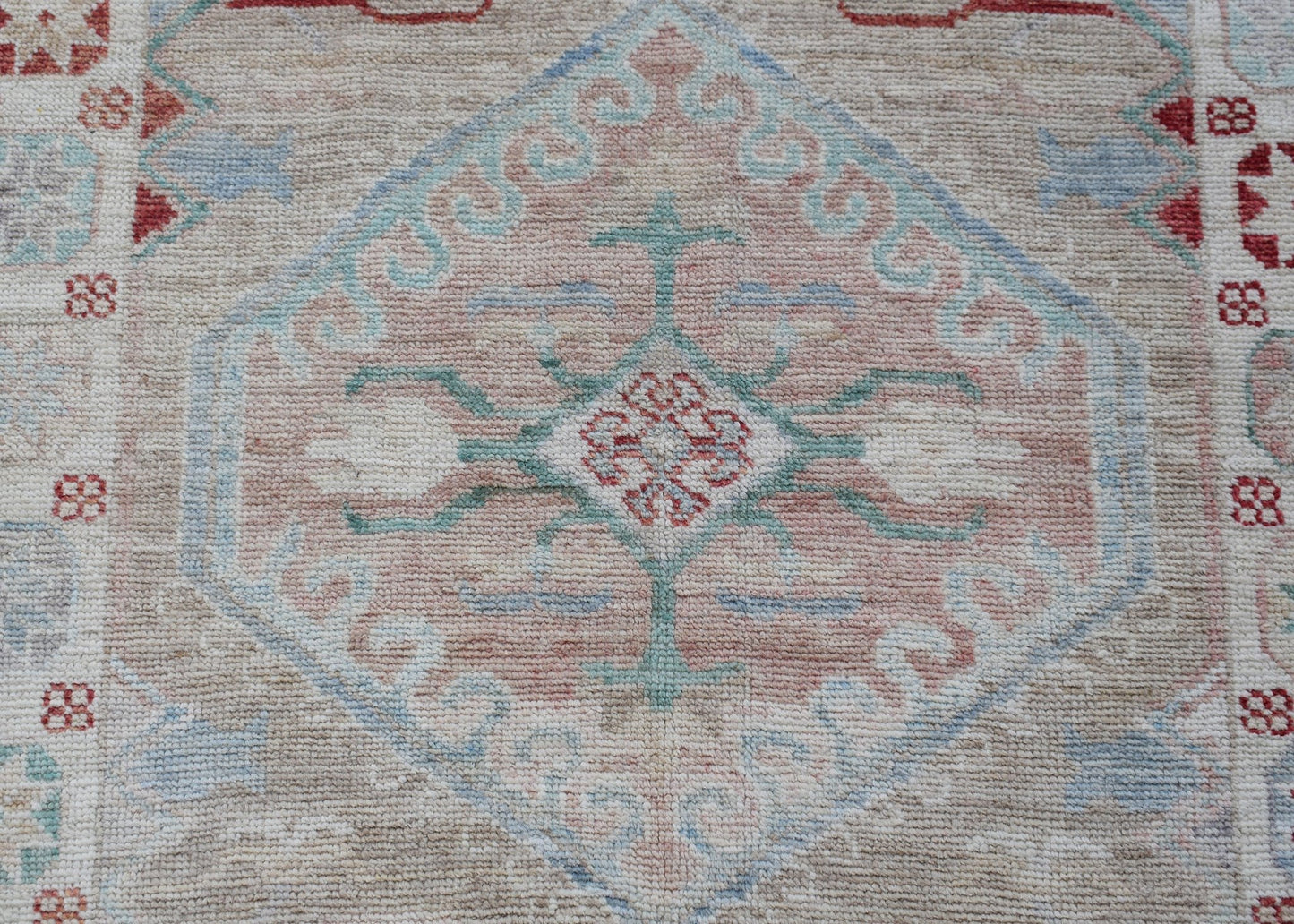 A handwoven transitional Oushak runner featuring a central floral medallion in soft pastel tones.