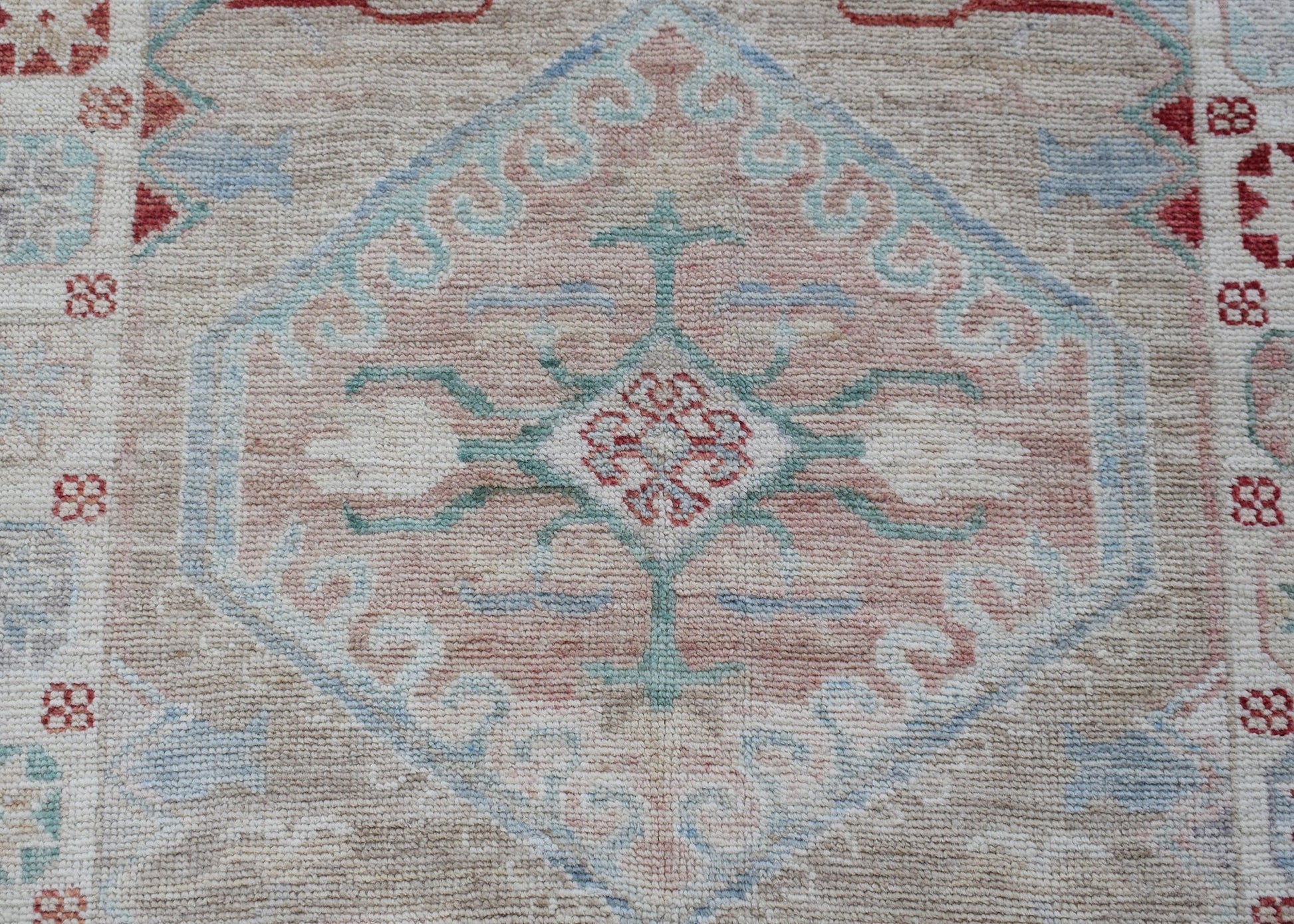 A handwoven transitional Oushak runner featuring a central floral medallion in soft pastel tones.