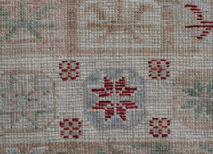 A handwoven Oushak runner featuring a geometric floral pattern in red, blue, and green on wool.